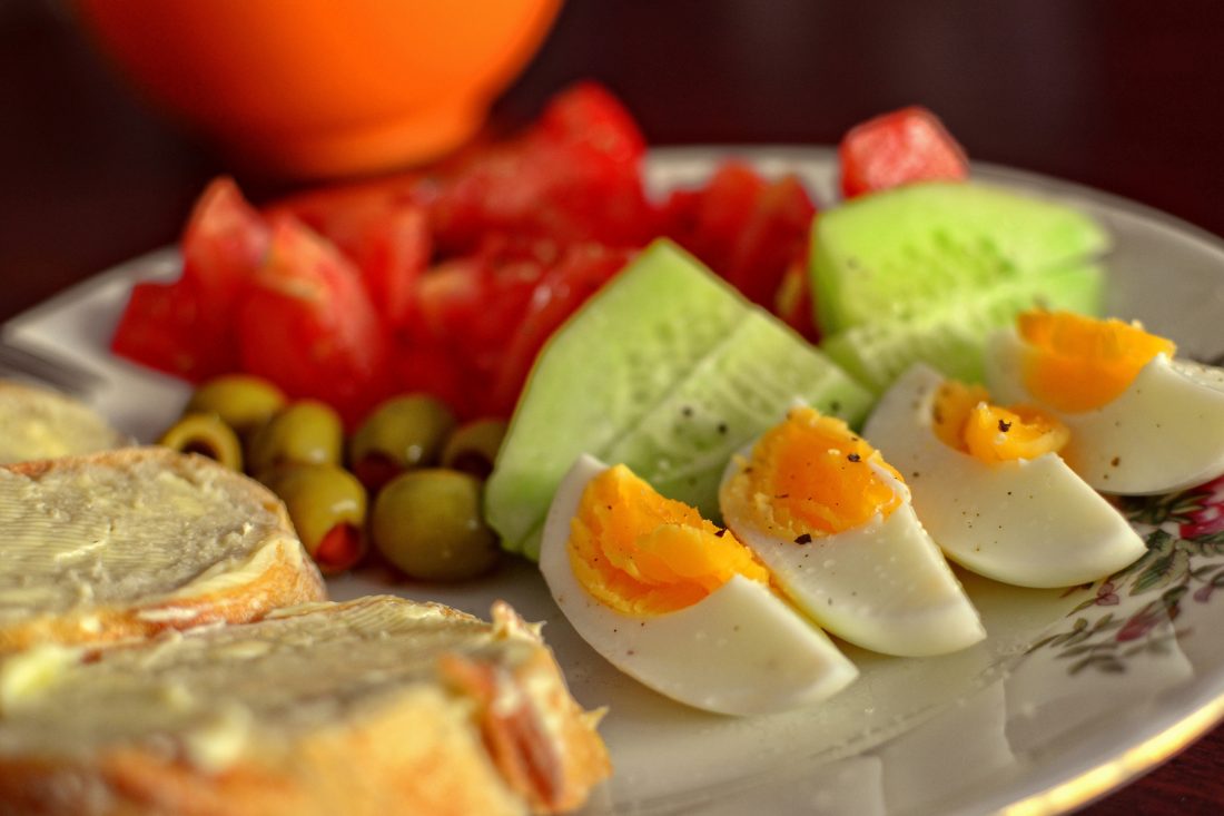 Boiled eggs, toast, cucumber and tomatoes on a breakfast plate