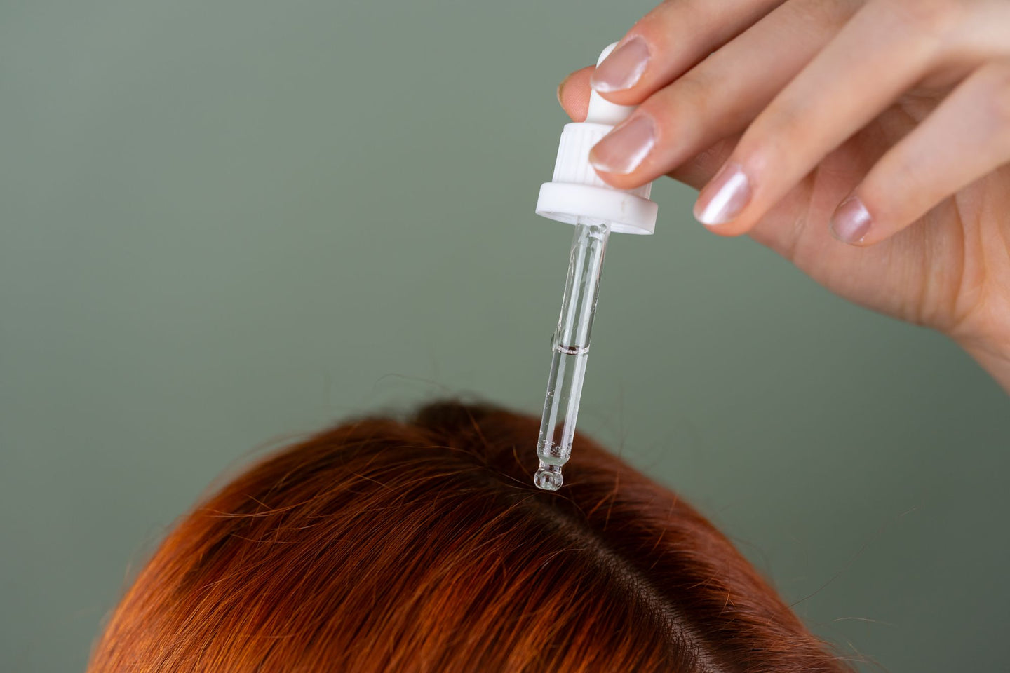 A dropper held above a visible part in red hair