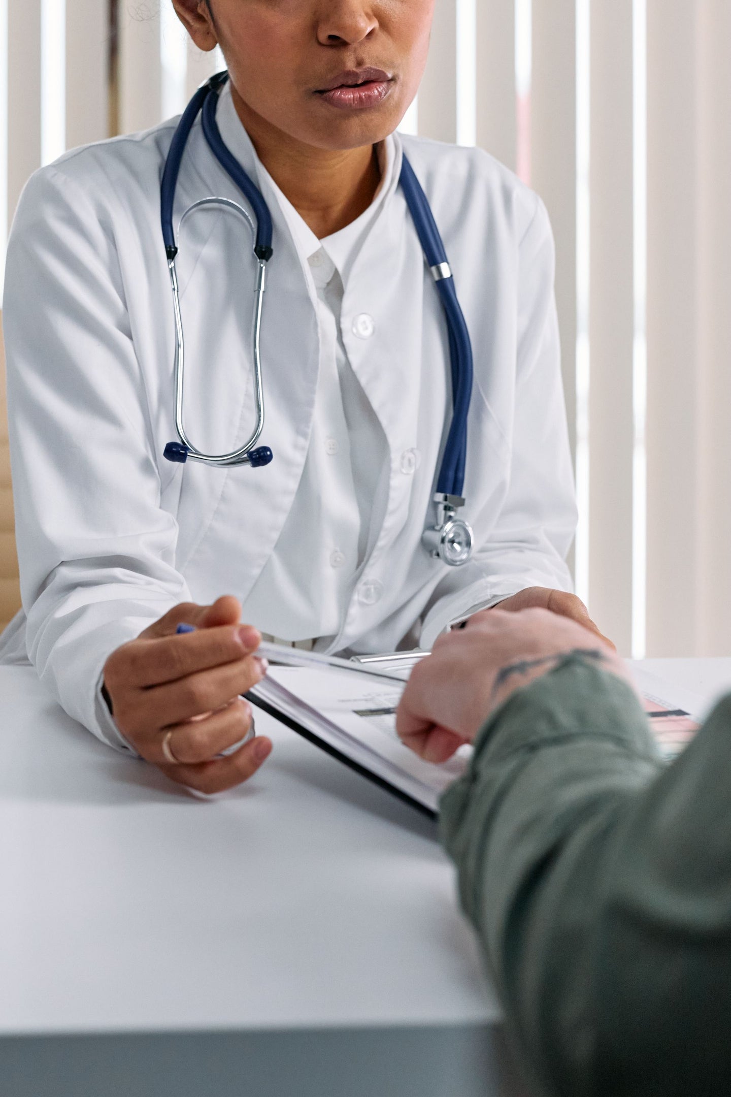 A clinician and a visitor discussing notes across a desk