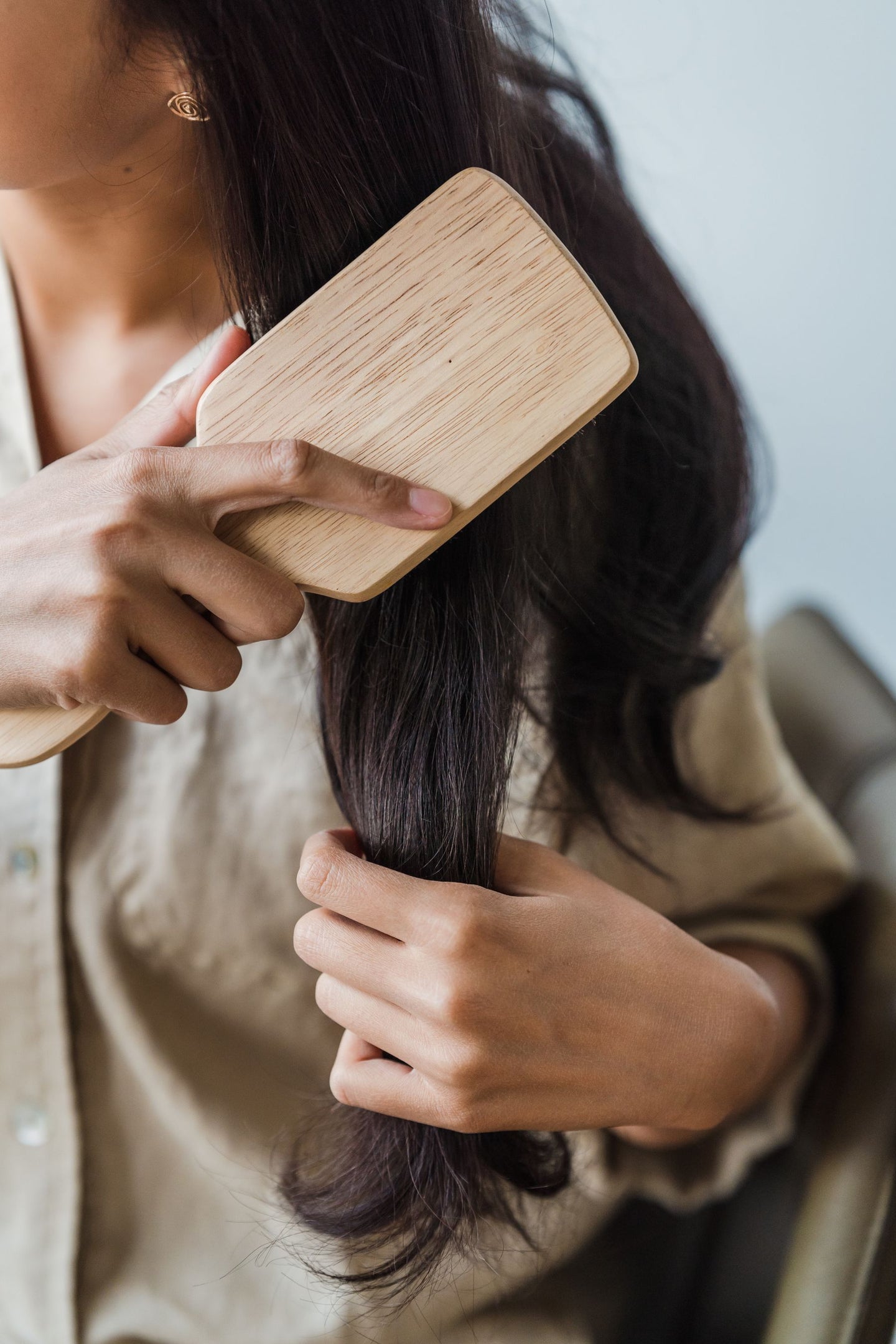 A wooden hairbrush moving through dark hair lengths