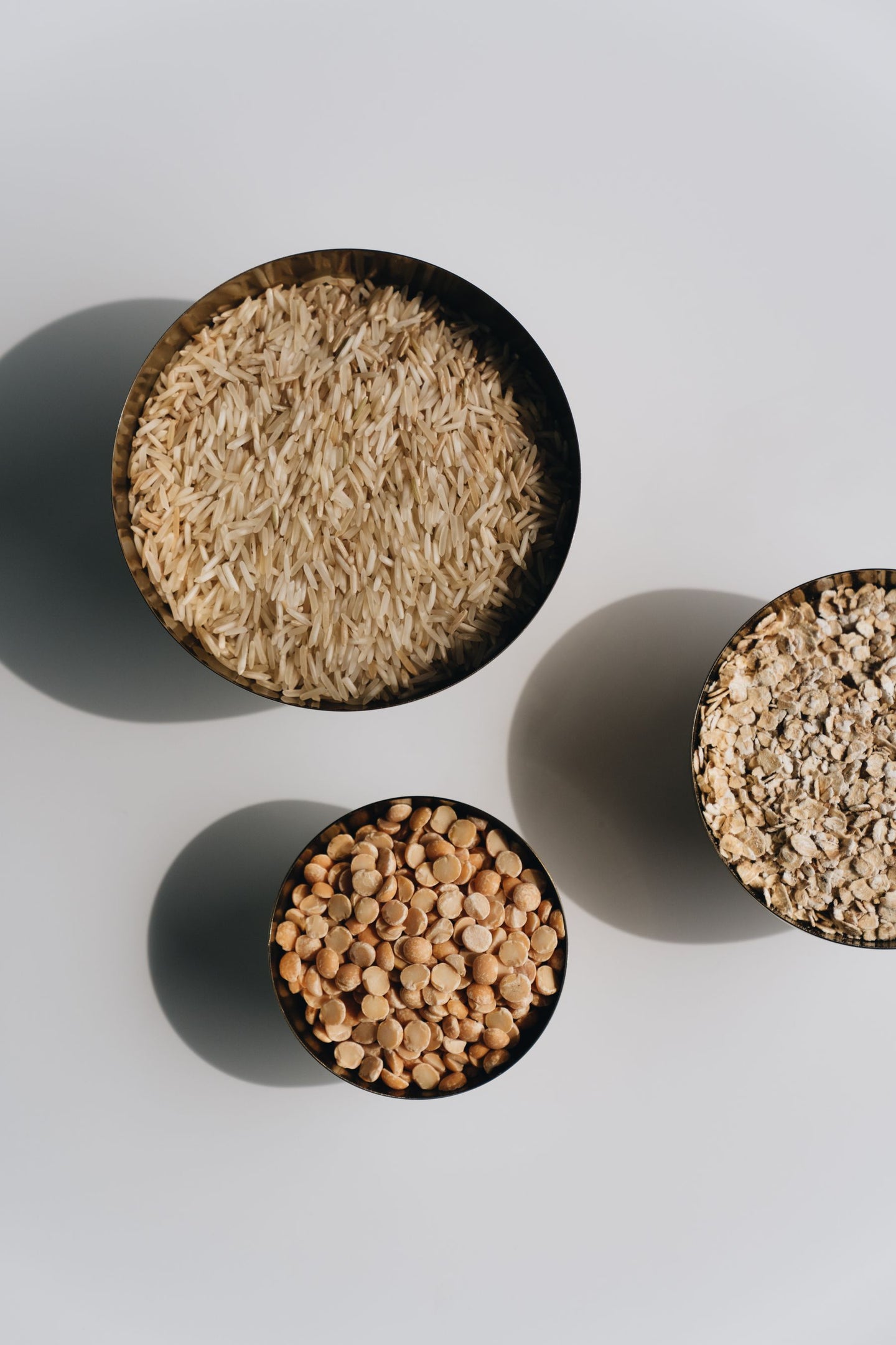 Bowls of rice, lentils and oats on a light surface