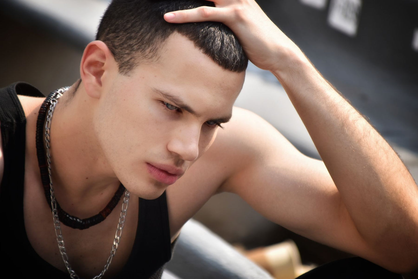 A man moving his hand over his short hair outdoors