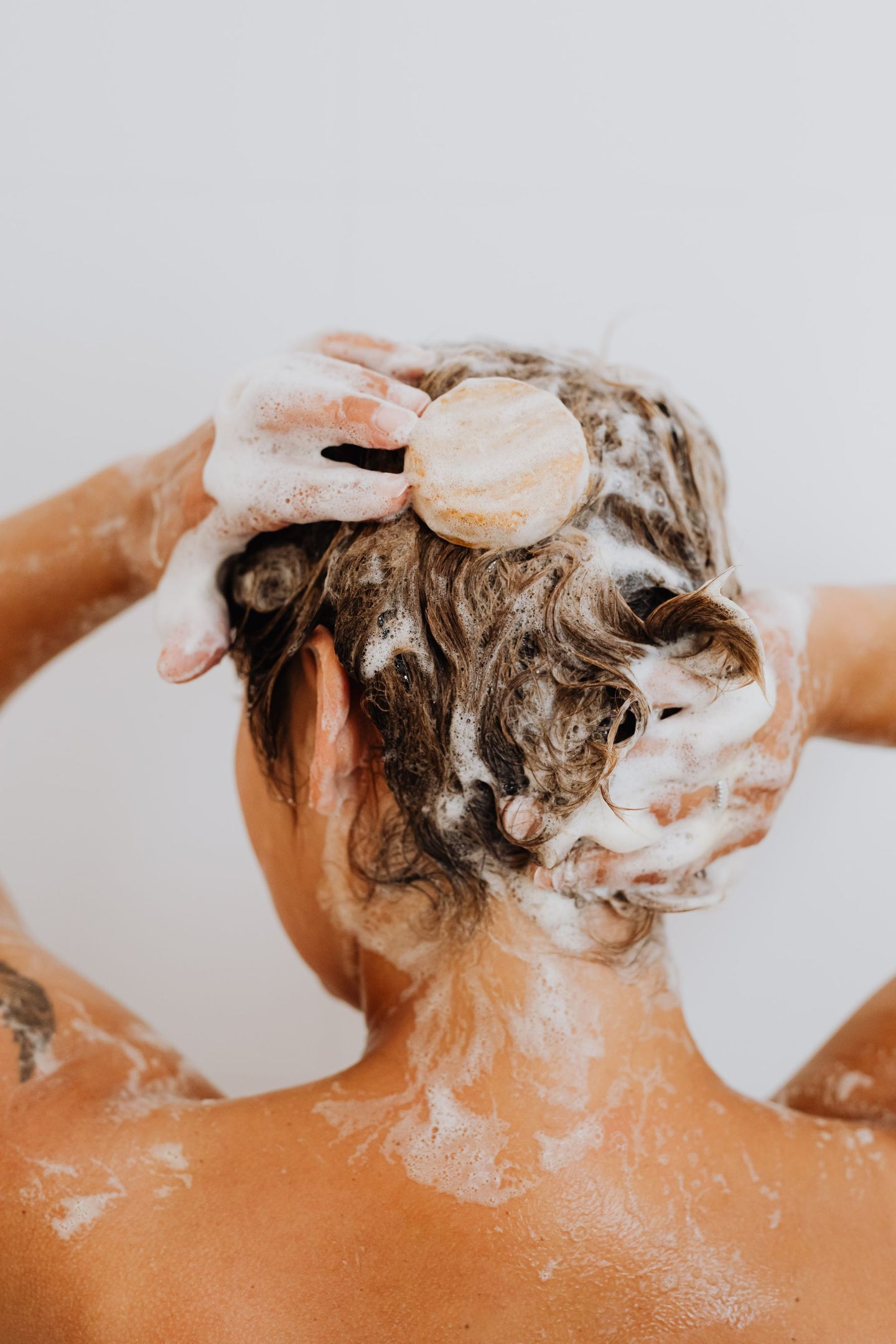 Hands working lather through hair during washing