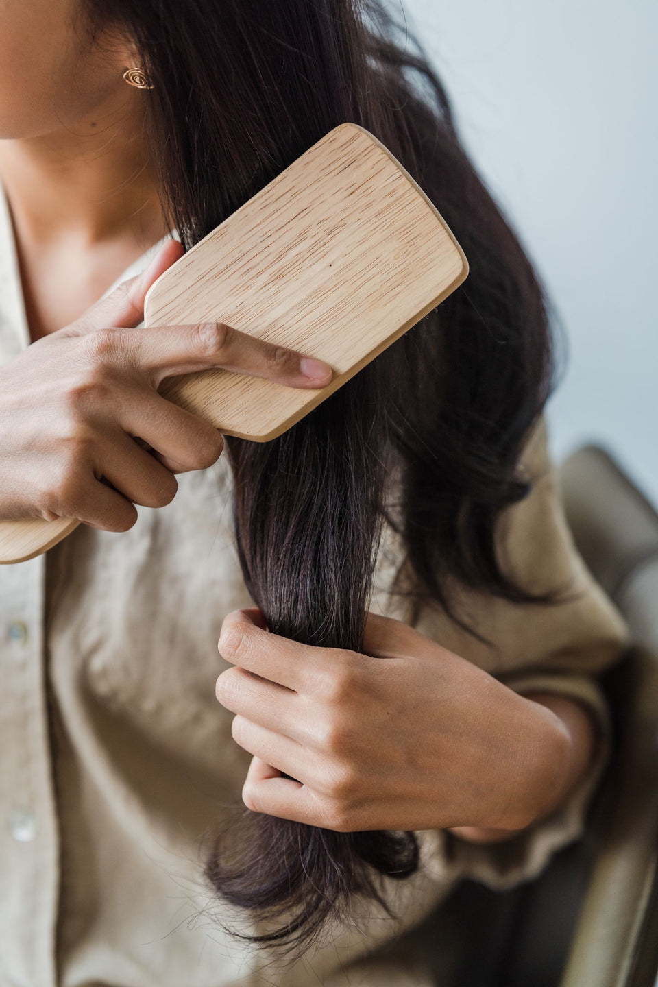 A wooden hairbrush moving through dark hair lengths