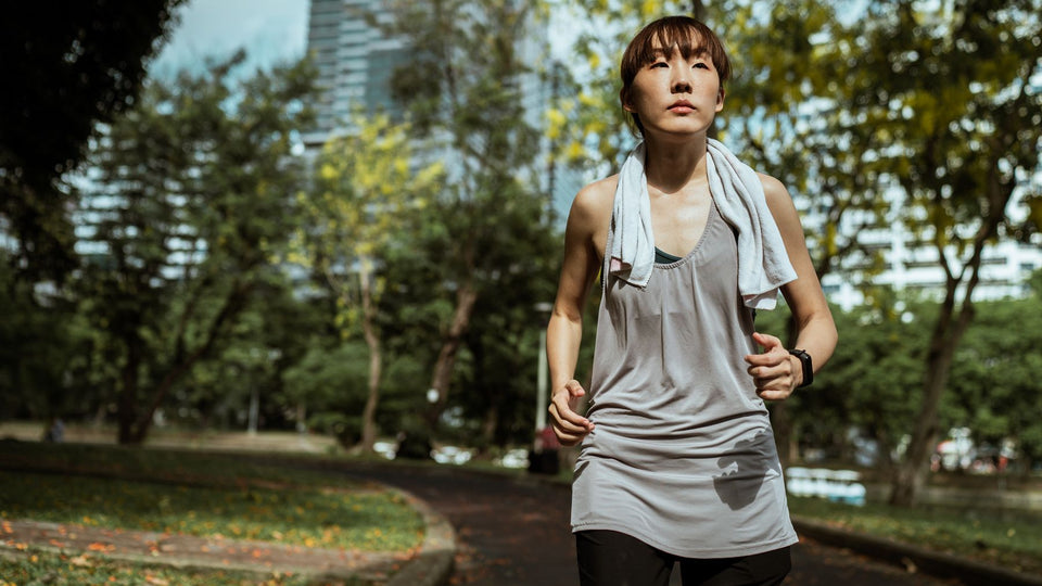 A woman running in a park with a towel around her neck