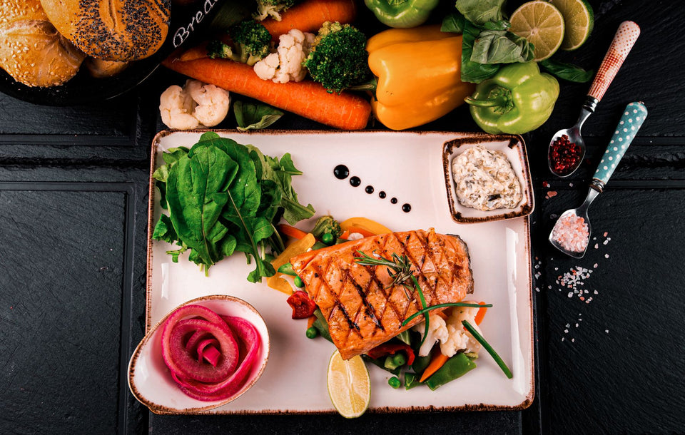 A plate of salmon with vegetables and greens