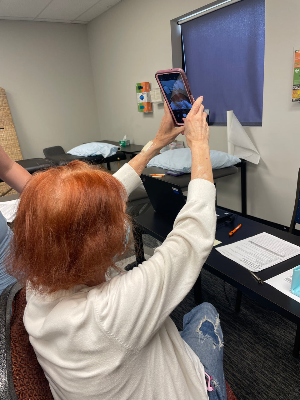 A woman holding a phone above her head to take a scalp photograph
