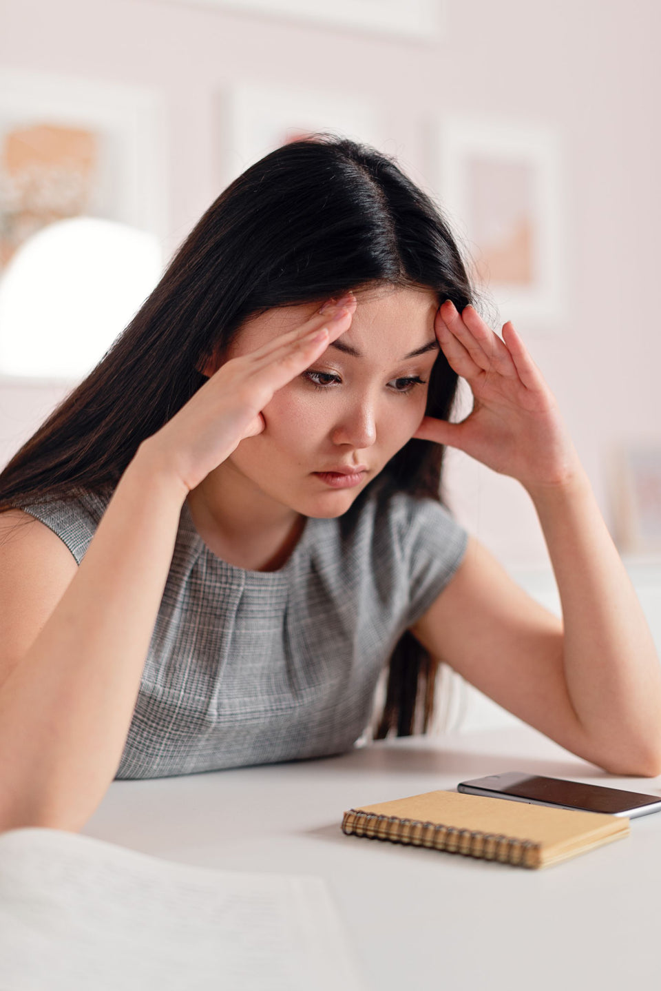 A woman at a desk resting her hands against her temples