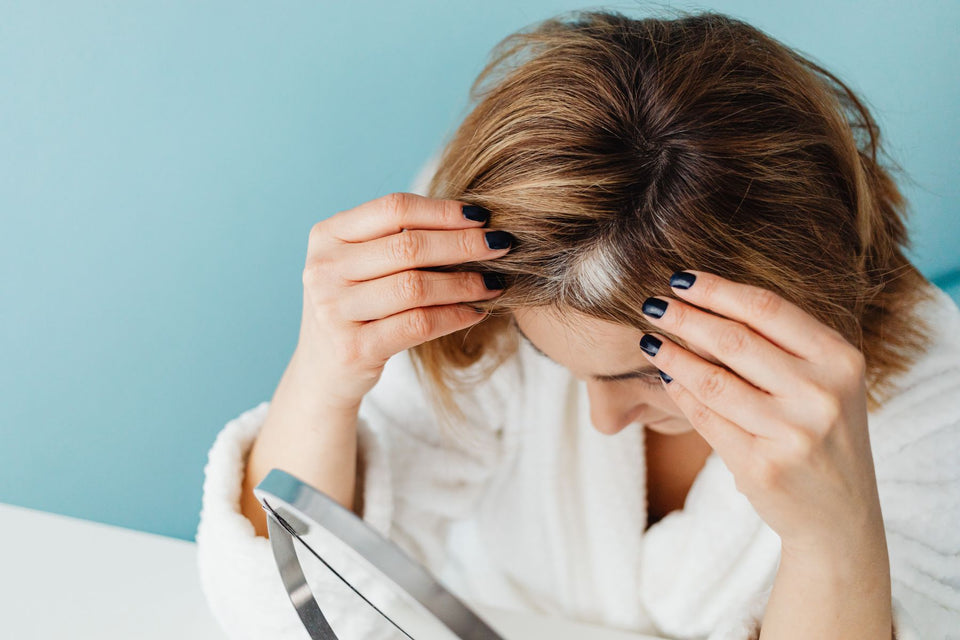 A woman checking her hair roots in a mirror