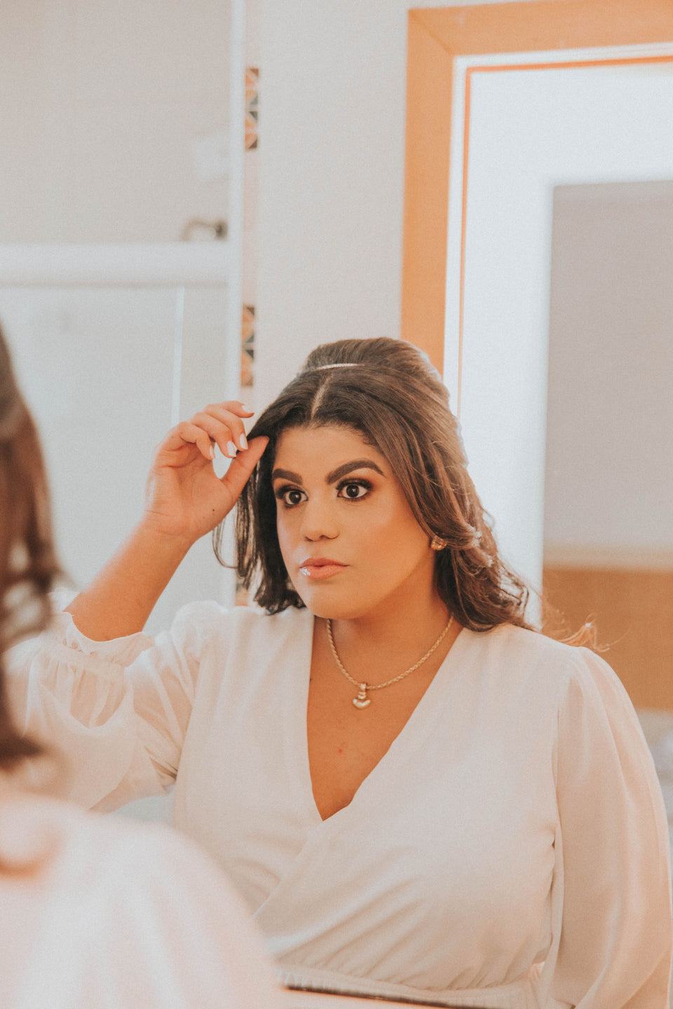A woman adjusting her hair while looking in a mirror